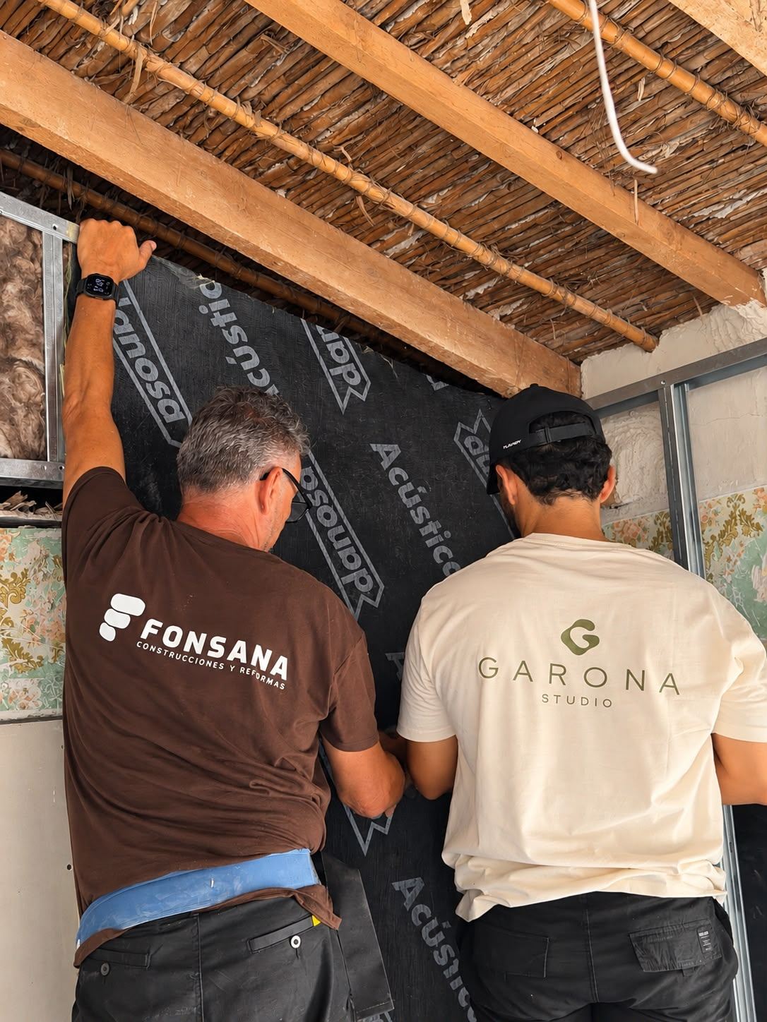 Dos personas del equipo instalando aislamiento acústico en una obra, una con camiseta de Garona Studio