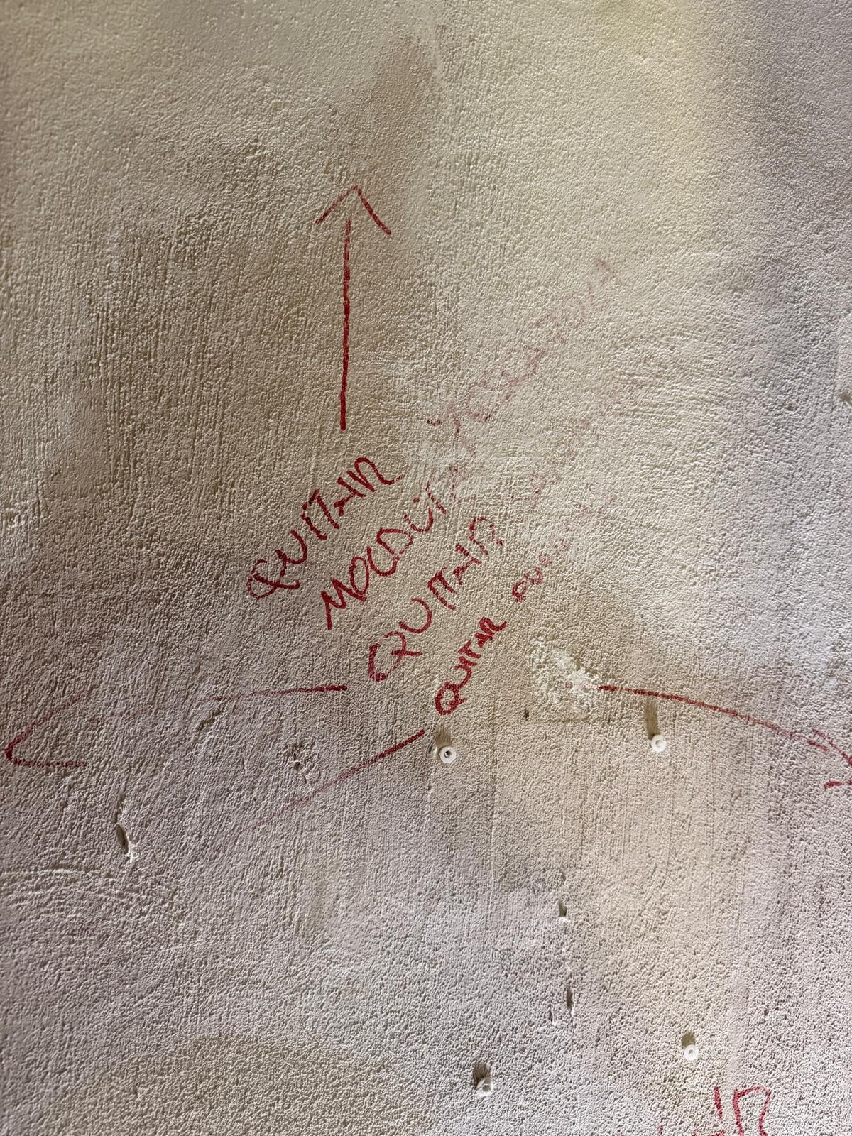 Pared en obra con anotaciones a mano en rojo para el replanteo