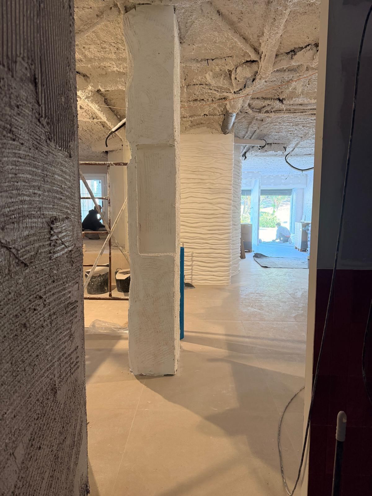 Local en obra con pilares revestidos y paredes con textura a medio terminar