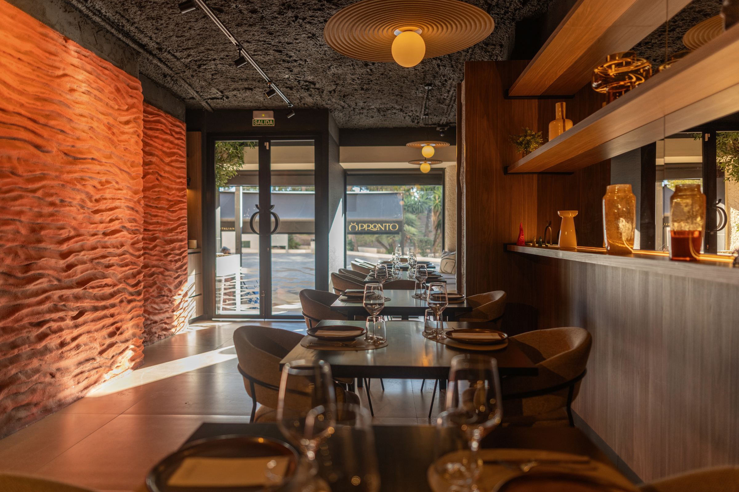 Comedor de Pronto con pared de textura volcánica roja, techo oscuro y barra de madera