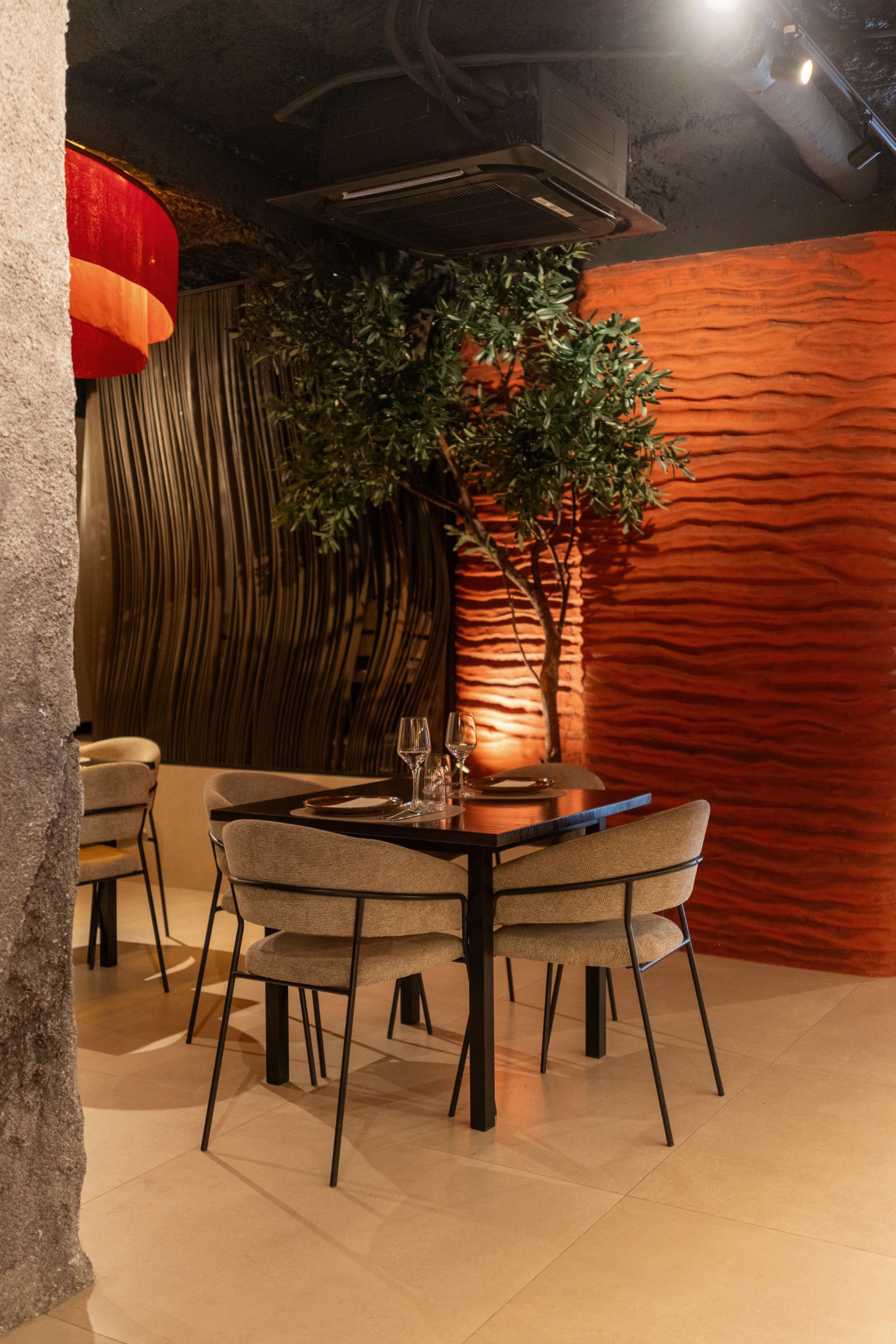 La misma pared ondulada terminada en rojo volcánico, iluminada junto a una mesa de Pronto