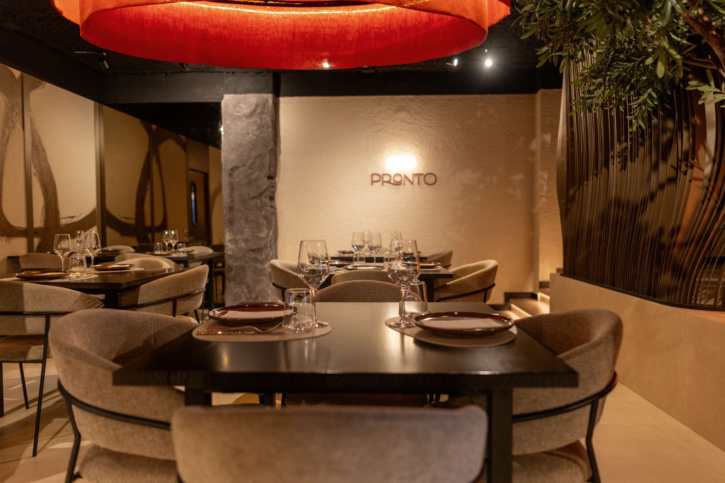Mesas del comedor bajo una gran lámpara circular roja, con el logotipo Pronto en la pared