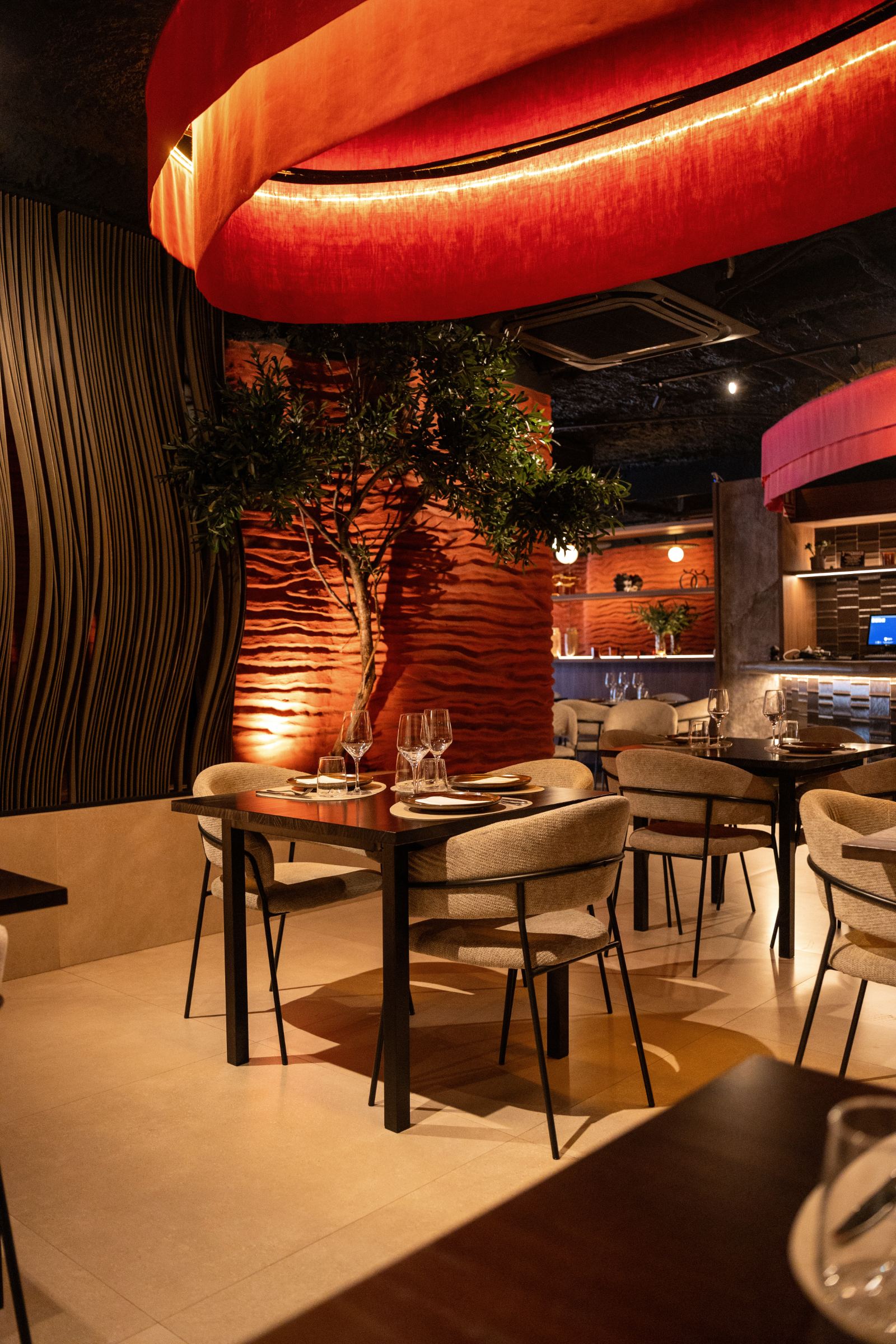 Rincón del comedor con árbol, pared ondulada iluminada y lámpara roja
